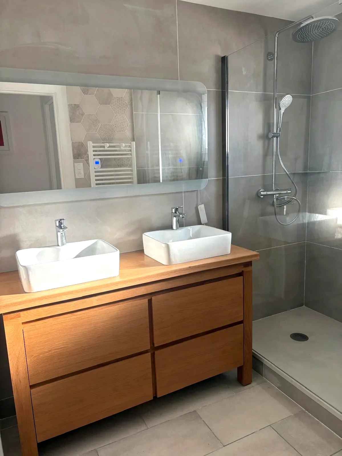 Aménagement d’une salle de bain : meuble double vasque, douche et carrelage clair